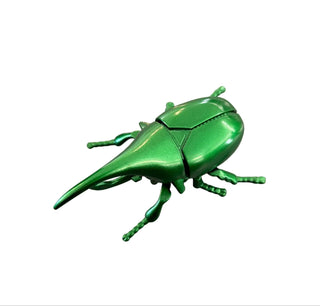 Green metallic beetle sculpture on a gray surface